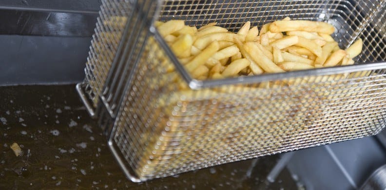 French fries being cooked in a basket in a restaurant.