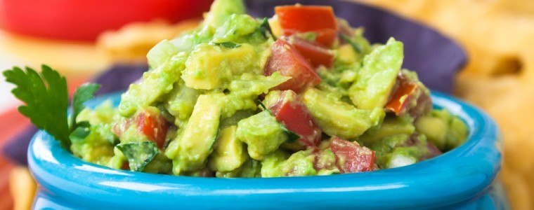 A bowl of guacamole and vegetables.
