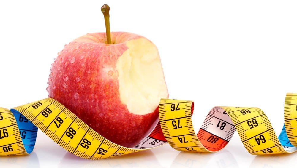 A bitten apple with measuring tape.