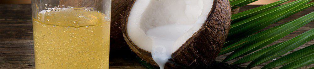 A glass of coconut oil next to a coconut shell.
