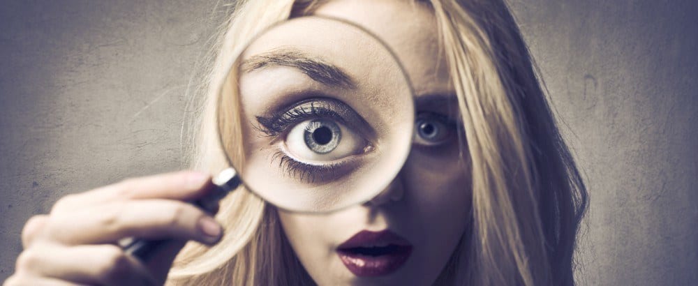 A woman looking through a magnifying glass with one eye.