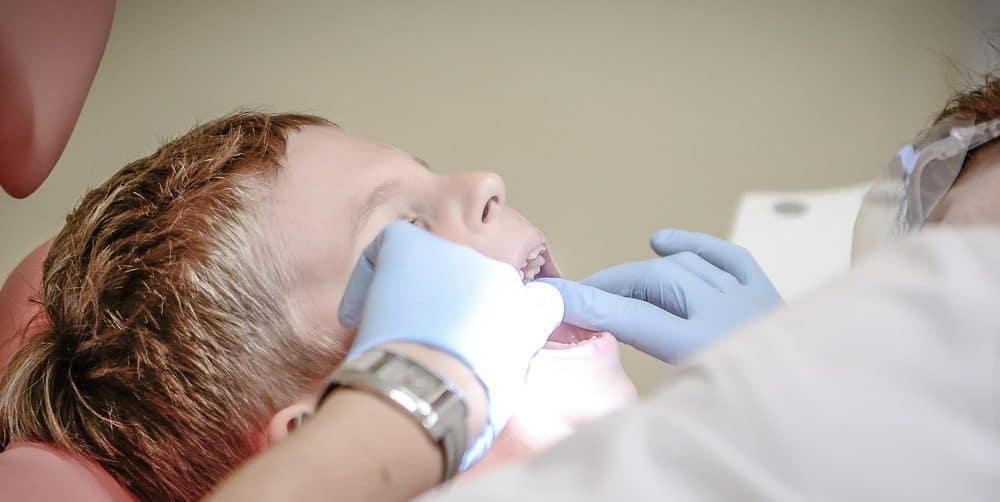 A dentist performing an oral inspection on a child.