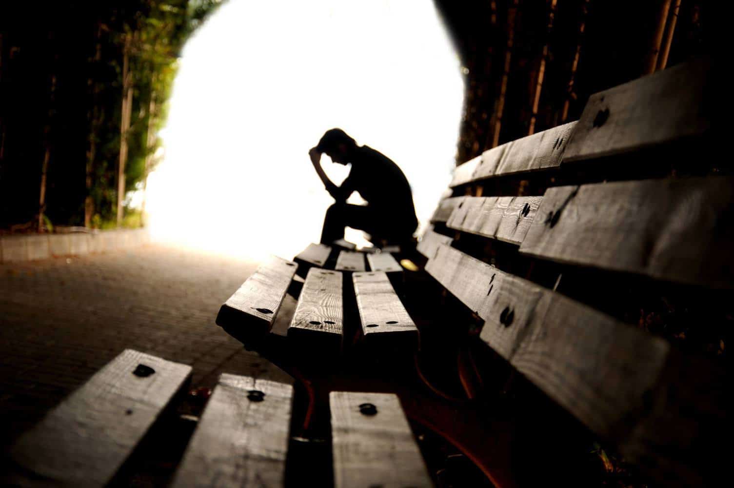 A depressed person sitting at a bench.