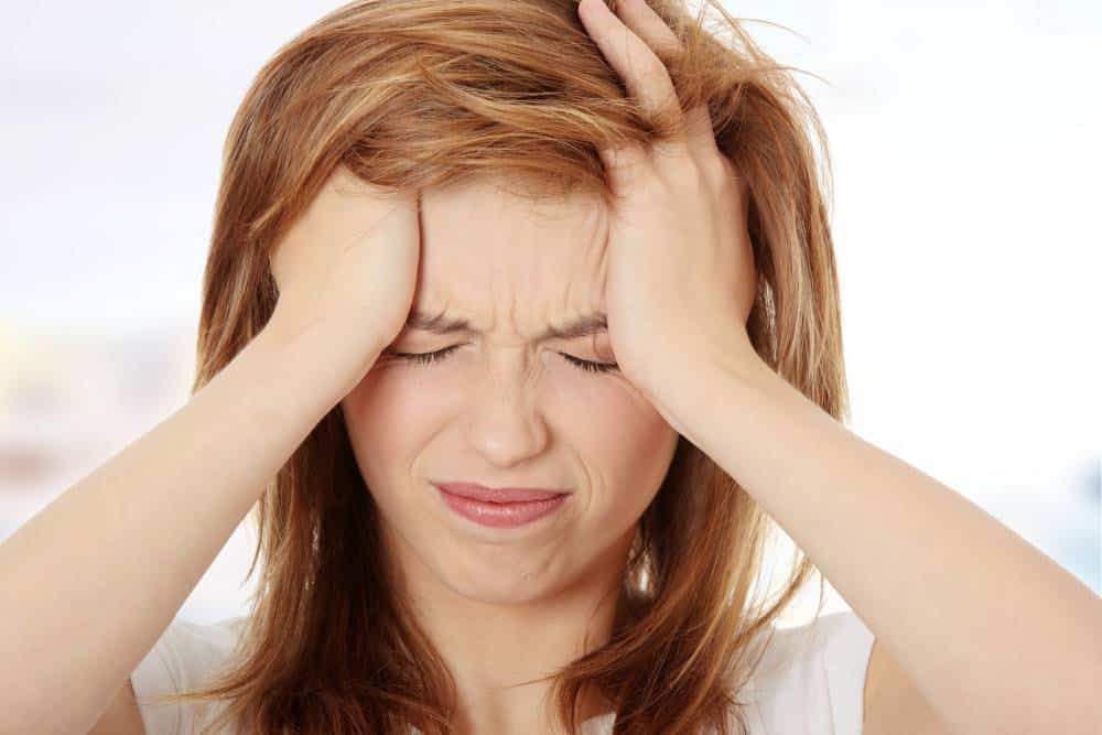 A woman holding her head because of a headache or migraine.