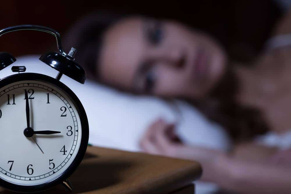A sleepless woman looking at her alarm clock.