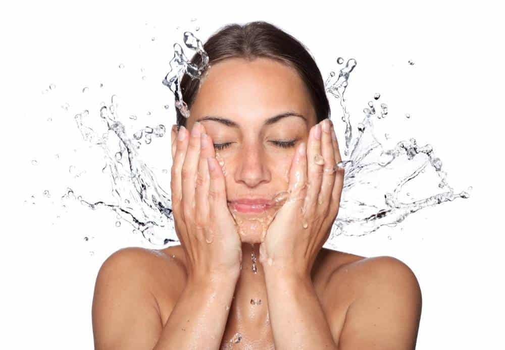 A woman splashing water on her face.