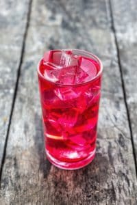 A glass of bright red juice with ice.
