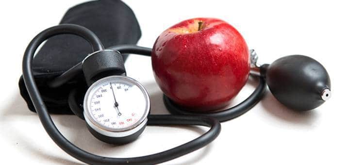 An apple next to a blood pressure monitor.