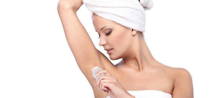 A woman applying deodorant to her armpit.
