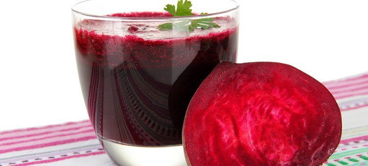 A glass of beet juice next to beetroot.