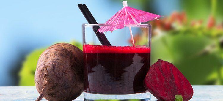 Beet juice in a glass next to beetroot.