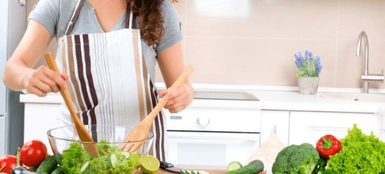 A woman preparing a salad in her kitchen.