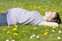 A woman sleeping on her back in the grass.