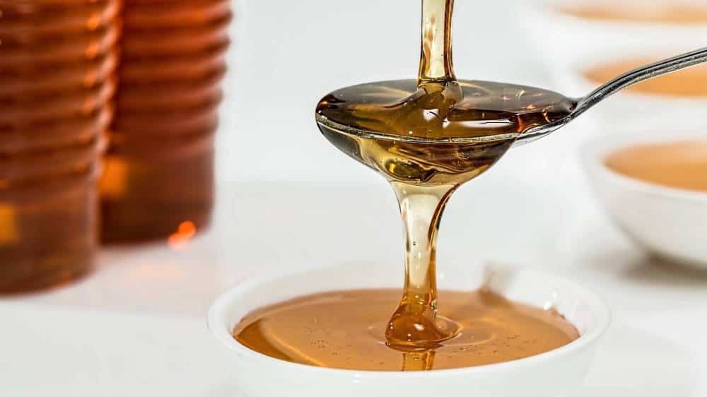 Honey being poured on a spoon.