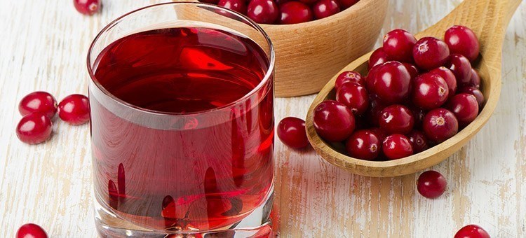 A glass of cranberry juice with a spoonful of cranberries.