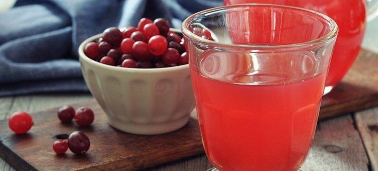 A glass of cranberry juice with a cup of cranberries.