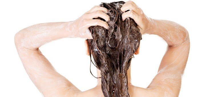 A woman washing her hair with shampoo.