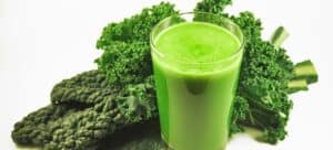A glass of kale juice next to some kale.