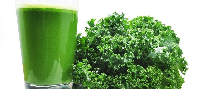 A glass of kale juice next to kale.