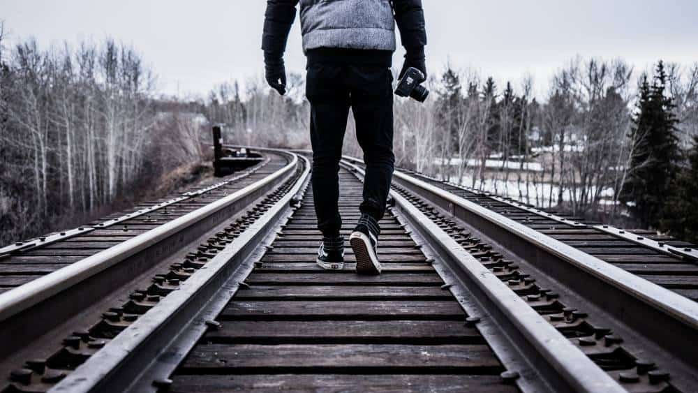 A person walking on train tracks in an urban setting.