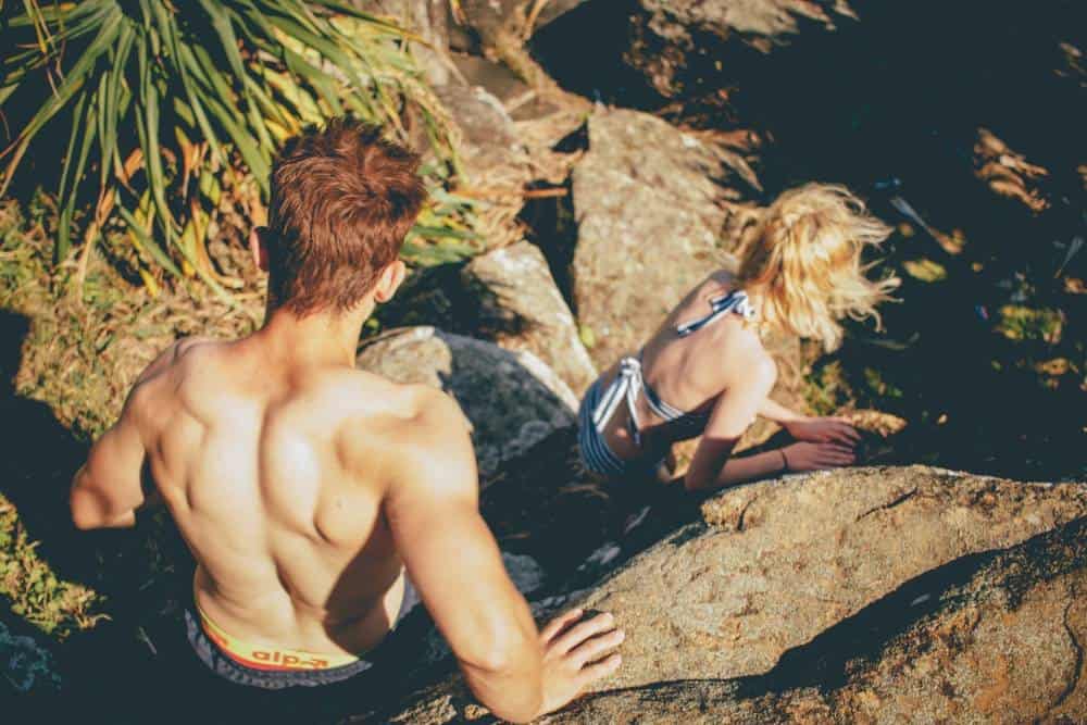 A couple hiking around nature in their swimsuit.