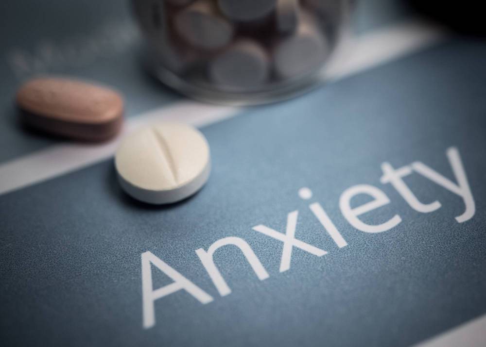 Anxiety written on a surface next to some tablets.