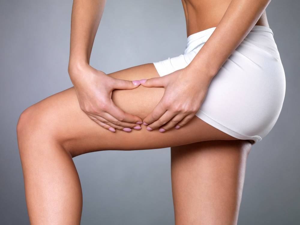 A woman checking her thighs for cellulite.