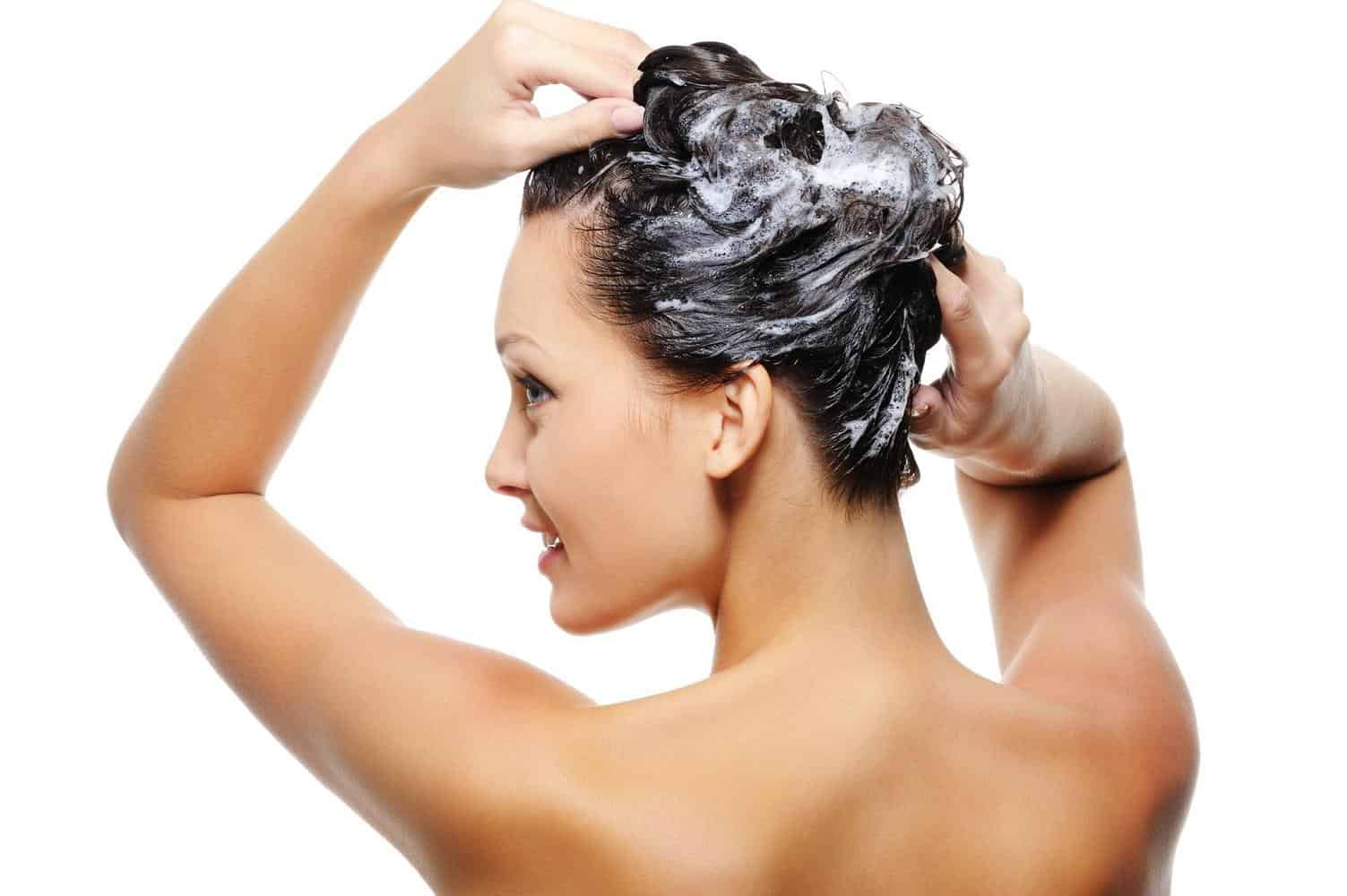 A woman applying shampoo to her hair.