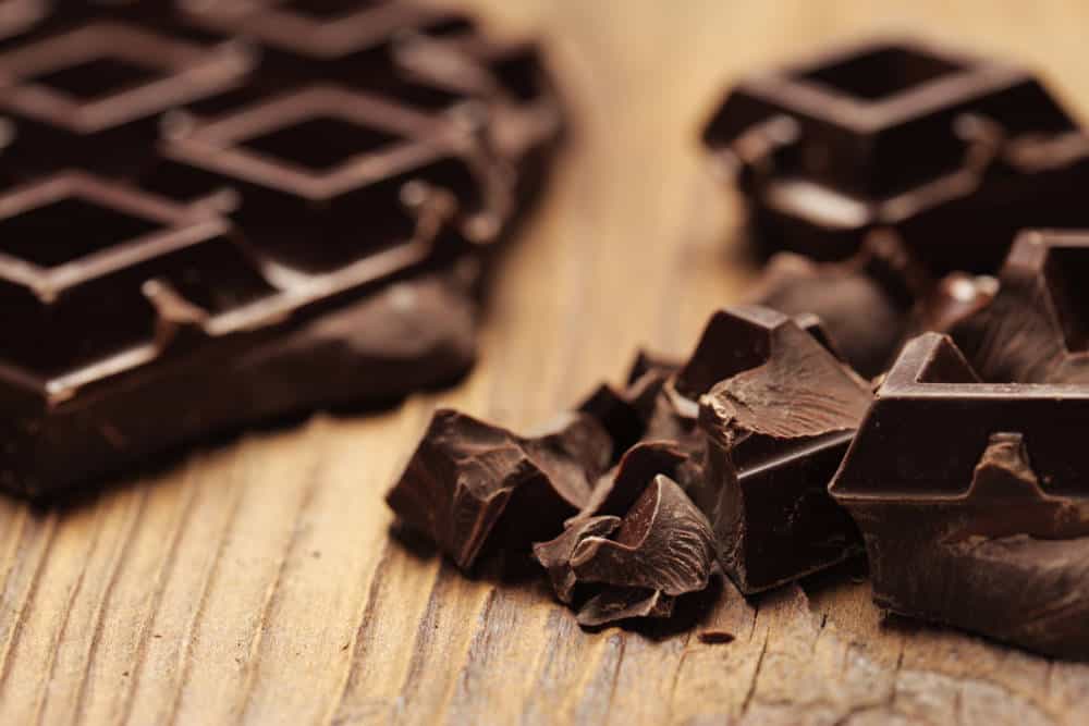 Pieces of dark chocolate on a wooden background