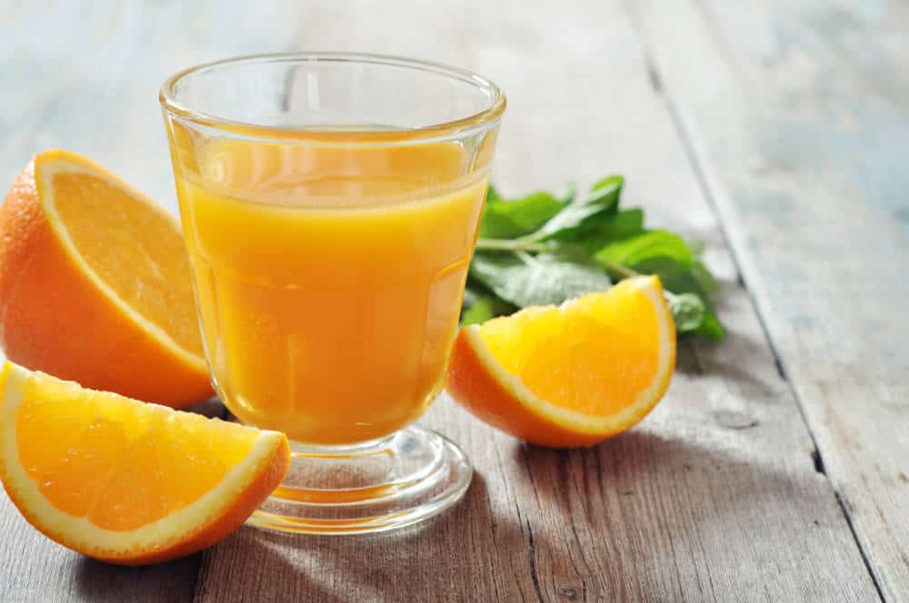 Orange juice in glass with mint, fresh fruits on wooden background