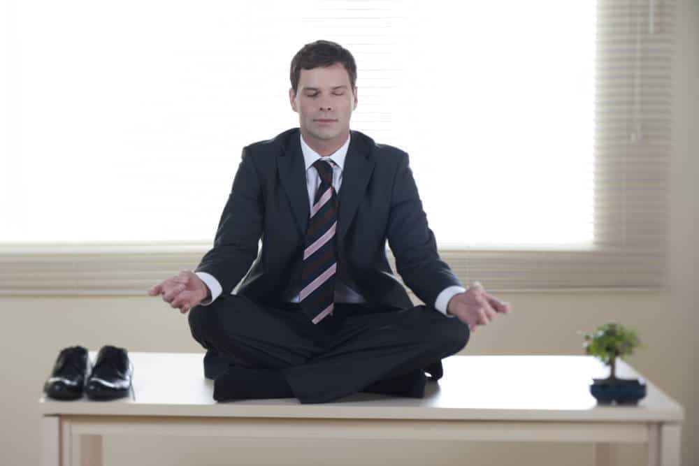 Young businessman meditating on his desk