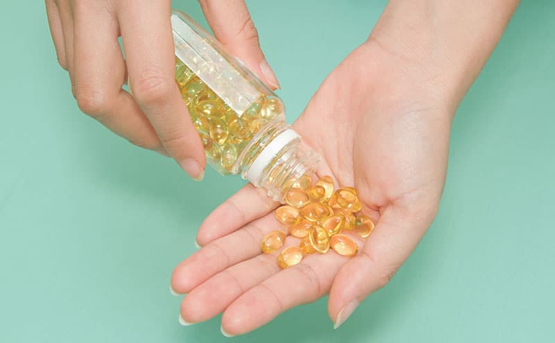 Woman 's hand take vitamin Omega-3 fish oil pills, which are one of the best anti inflammatory supplements to be found.