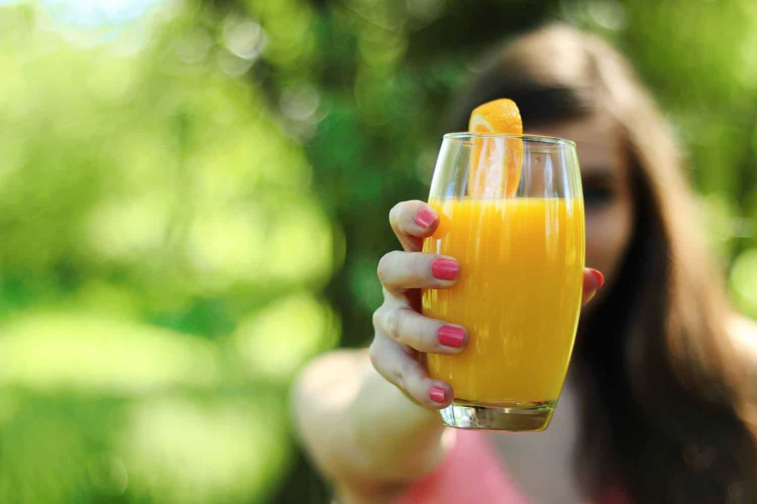 A girl holding a glass of orange juice.