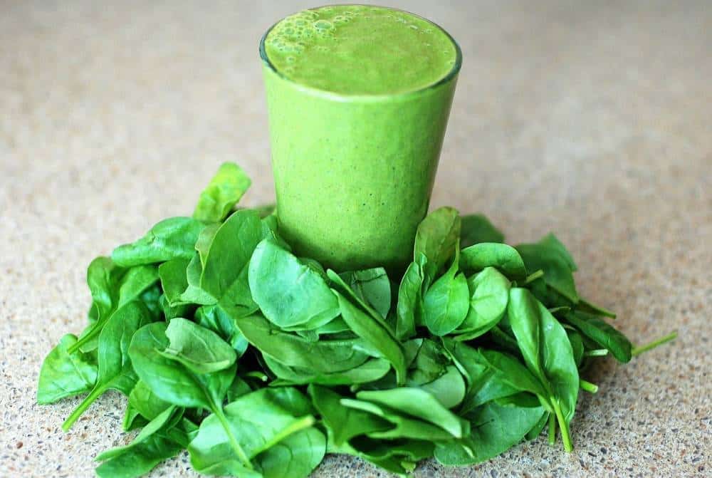 A glass of spinach juice with spinach.