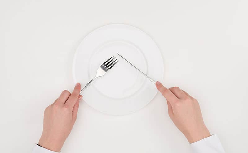 Two hand using a knife and a knife to cut the air on an empty white plate, on white background.