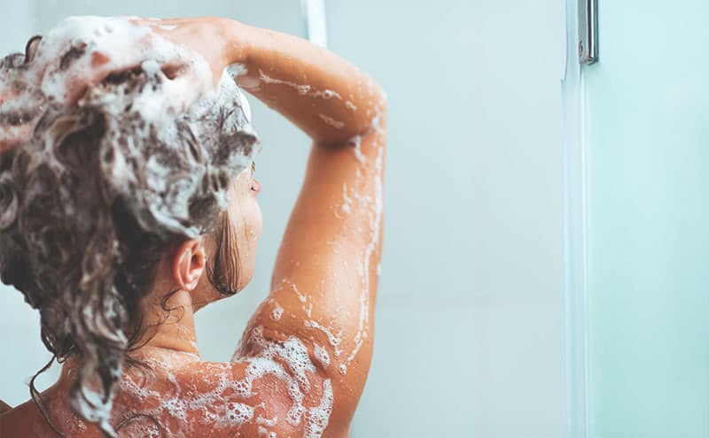 Woman in the shower washing her hair with the best shampoo for psoriasis.