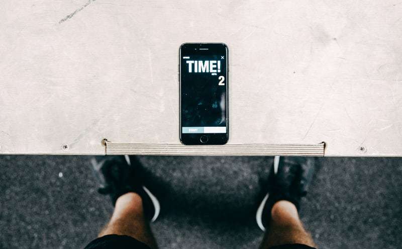 Sportsman using smartphone with time tracker in gym.